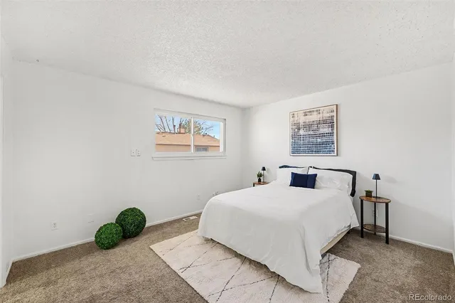 a bedroom with a bed a wall painting and a window