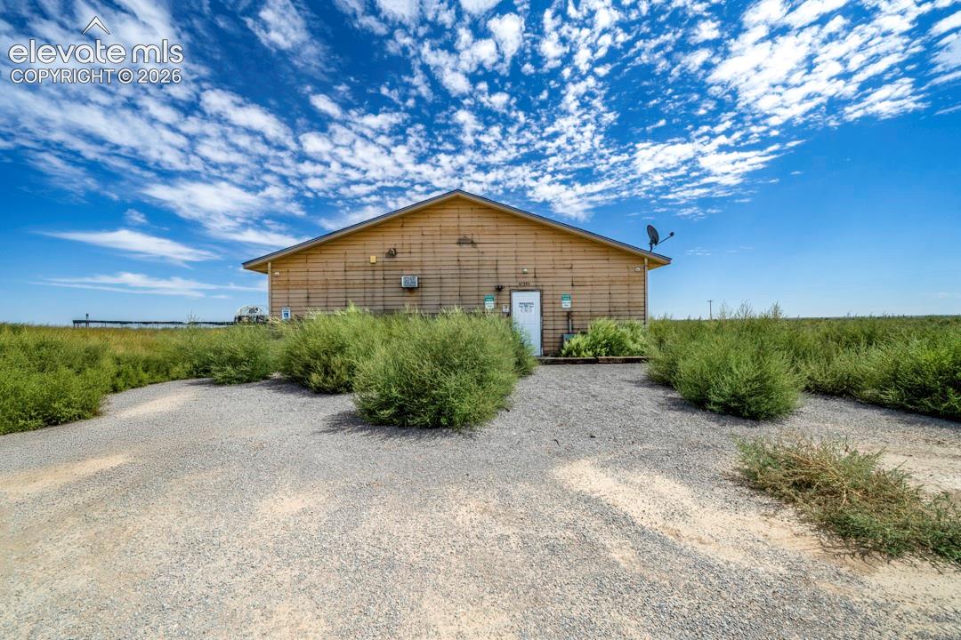 41751 Harbour Road Avondale, CO 81022 - Photo 22 of 41 Gable roof structure with wood-finish siding, featuring a white entry door and gravel parking