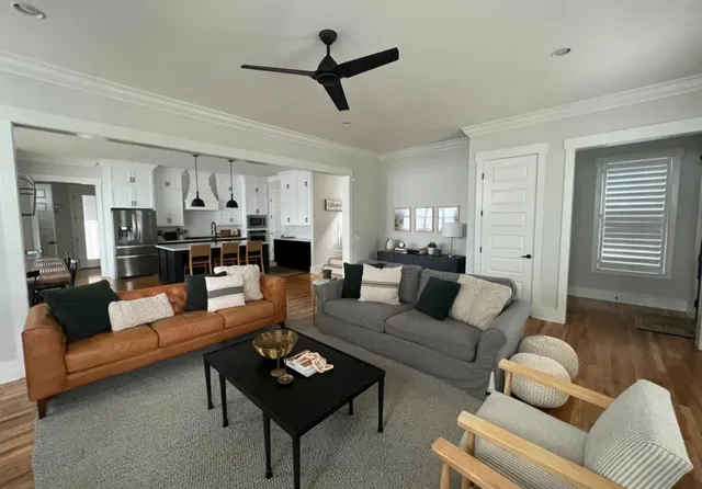 a living room with furniture kitchen view and a wooden floor