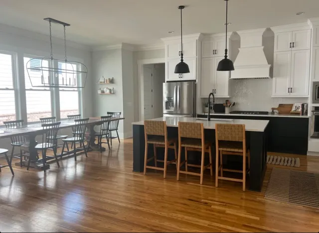 a open kitchen with granite countertop a stove a sink a dining table and chairs with wooden floor