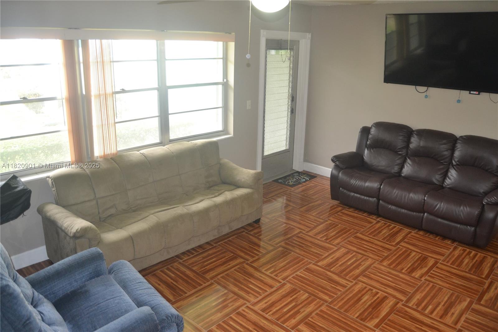 56 Norwich C, Unit 56 West Palm Beach, FL 33417 - Photo 4 of 23 a living room with a couch and a flat screen tv