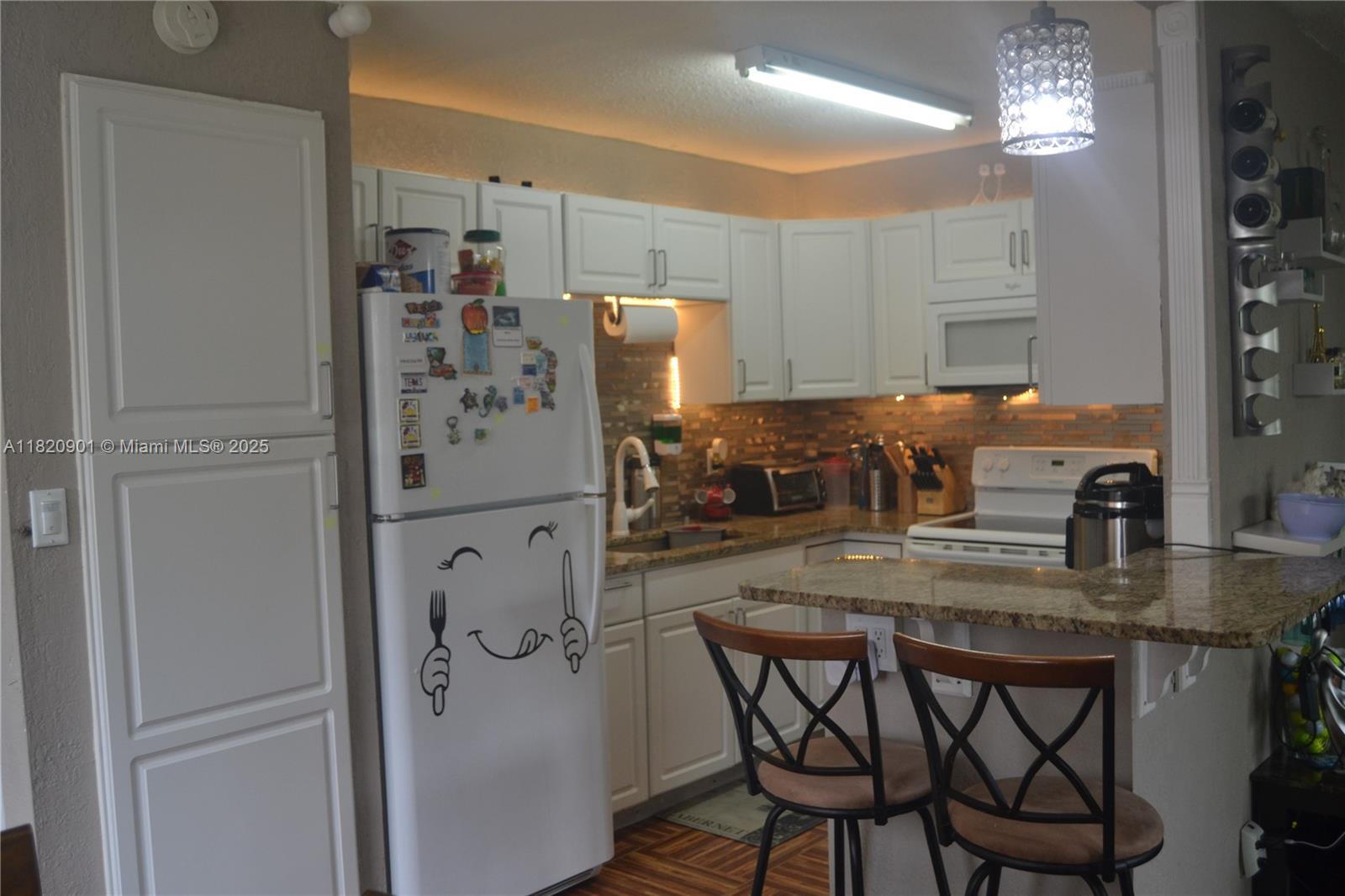 56 Norwich C, Unit 56 West Palm Beach, FL 33417 - Photo 8 of 23 a kitchen with stainless steel appliances granite countertop a dining table chairs and granite counter tops