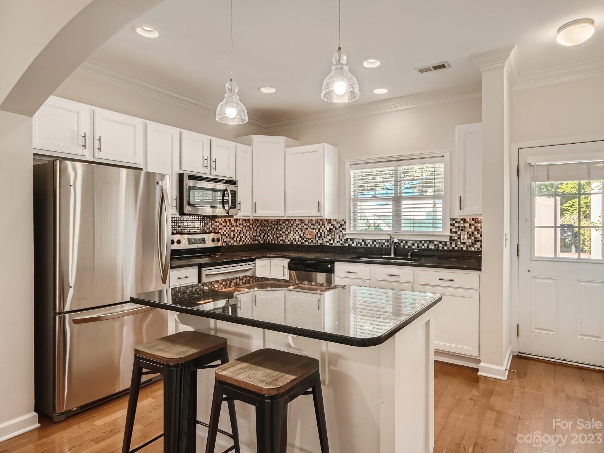 4130 Walker Road Charlotte, NC 28211 - Photo 9 of 28 a kitchen with stainless steel appliances granite countertop a refrigerator a sink a stove a dining table and chairs