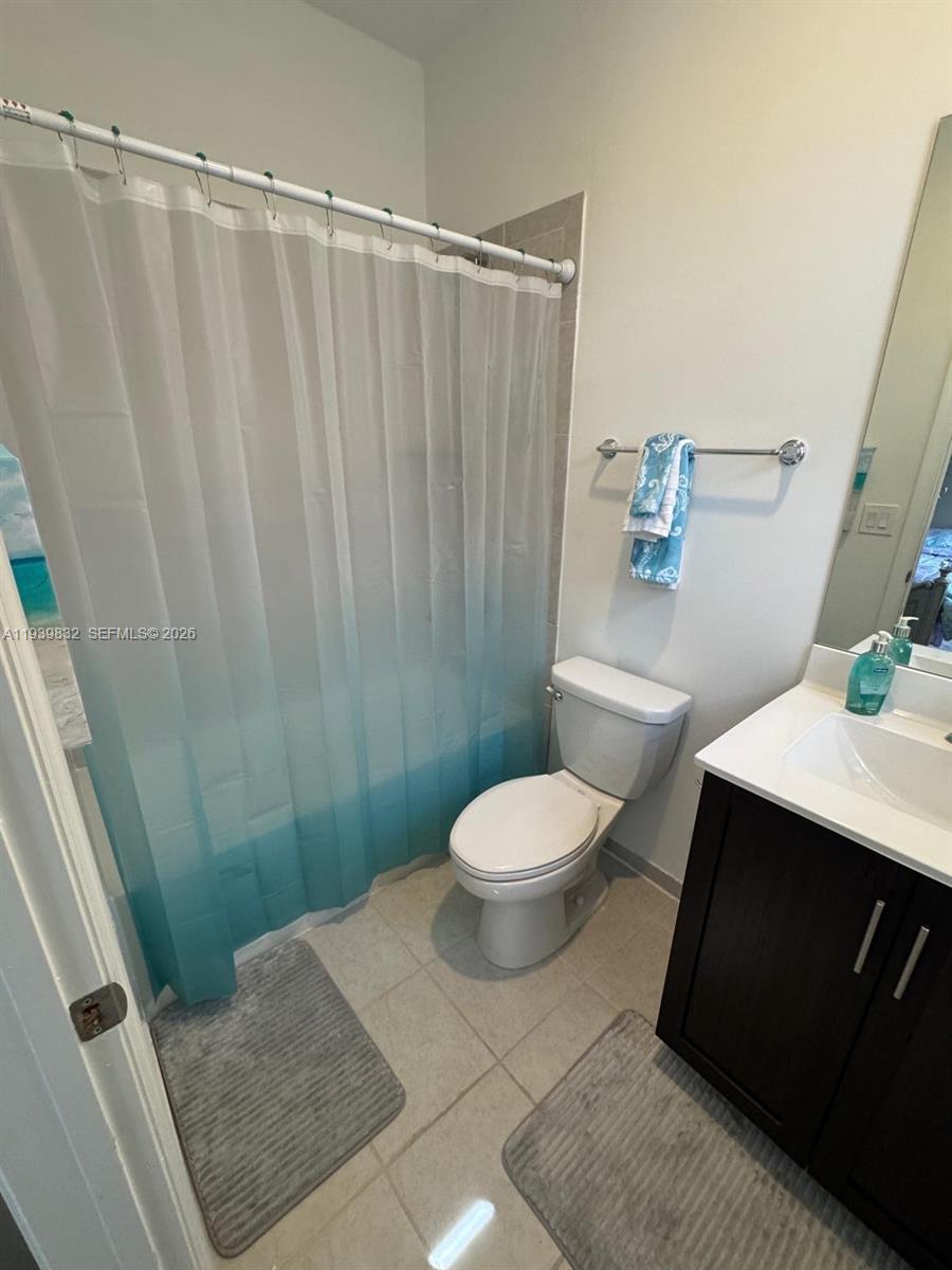 18236 Southwest 148th Road Miami, FL 33187 - Photo 3 of 9 a bathroom with a sink a toilet a shower curtain and a bath tub