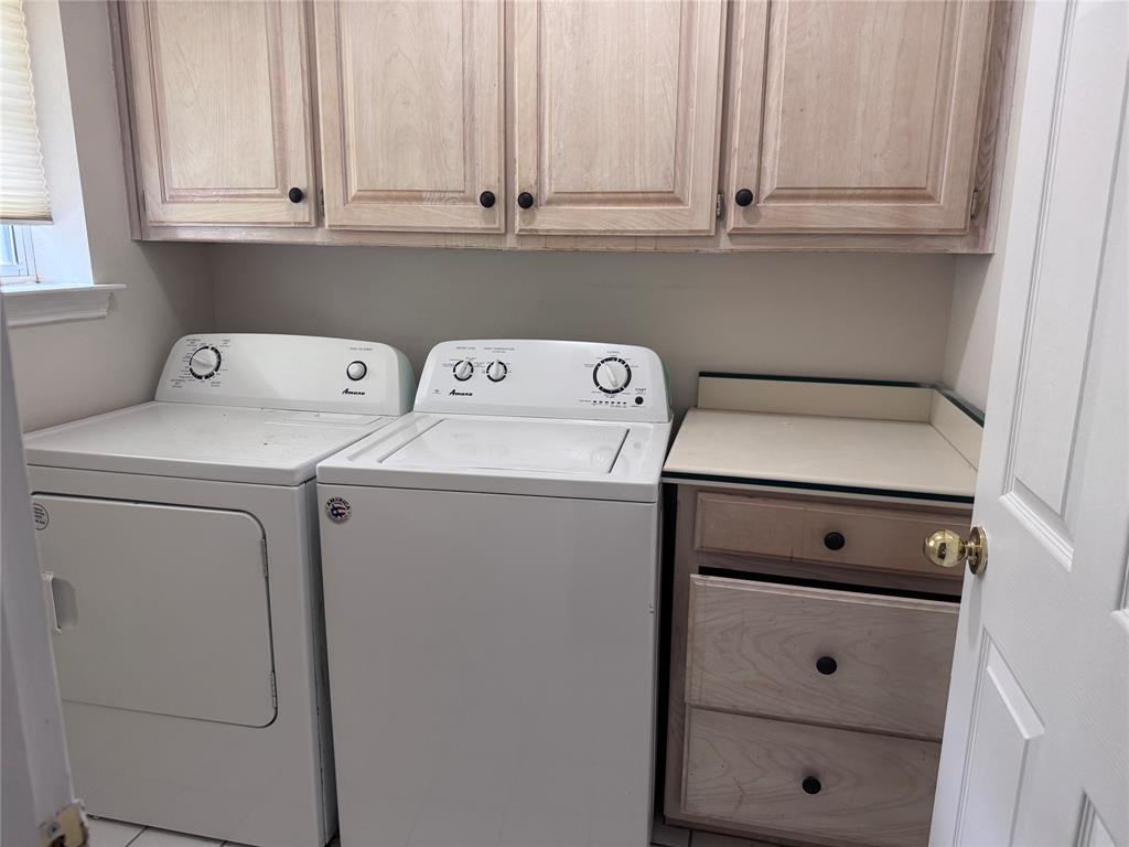 1704 South Bowen Road Pantego, TX 76013 - Photo 21 of 37 Dedicated laundry area featuring upper wood cabinetry with black hardware, a light-toned countertop, and integrated storage drawers-Clothes Washer and Dryer provided