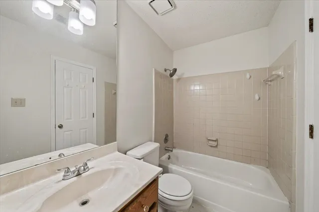 a bathroom with a bathtub shower sink vanity mirror and toilet