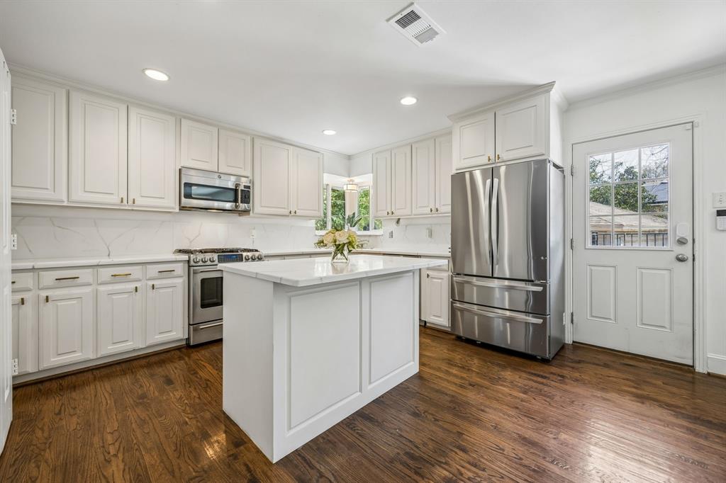 5130 Rexton Lane Dallas, TX 75214 - Photo 14 of 28 a kitchen with kitchen island white cabinets and stainless steel appliances