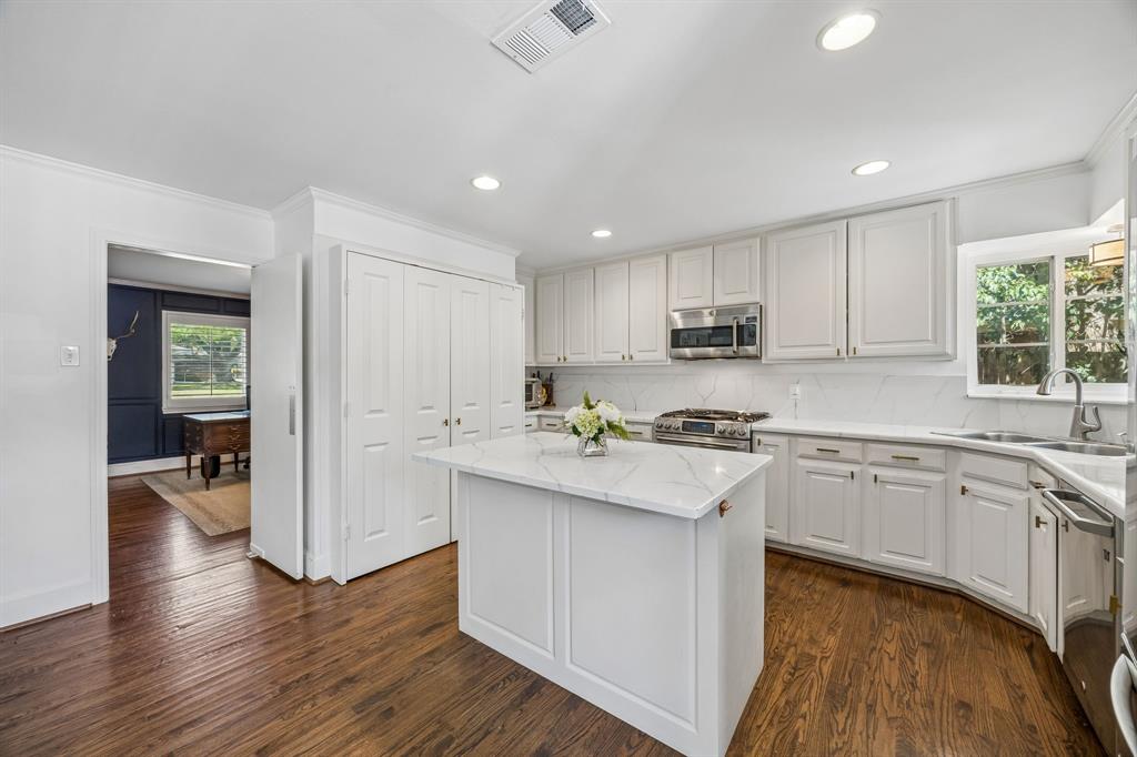 5130 Rexton Lane Dallas, TX 75214 - Photo 16 of 28 a kitchen with stainless steel appliances granite countertop wooden cabinets a sink a stove a dining table and chairs