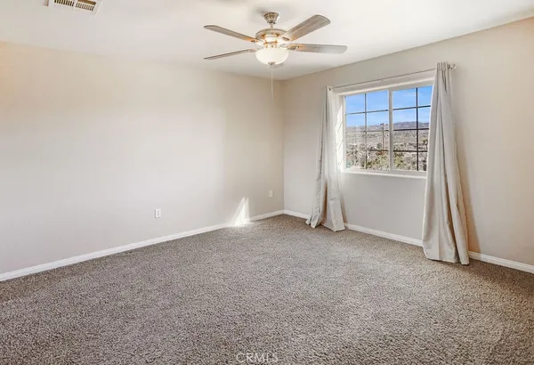 an empty room with windows and fan