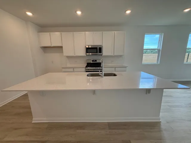 a kitchen with kitchen island a stove a sink and a refrigerator