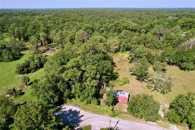an aerial view of residential houses with outdoor space and trees all around