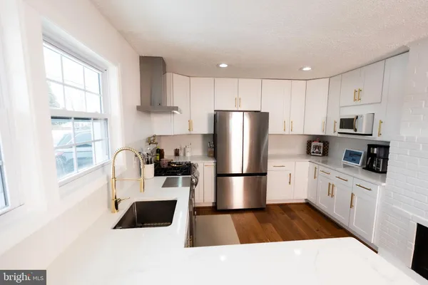 a kitchen with stainless steel appliances a refrigerator a stove a sink a microwave and white cabinets