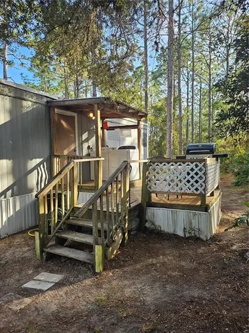 a view of a small yard with wooden fence and large trees