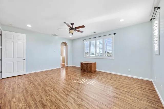 a view of empty room with wooden floor and fan