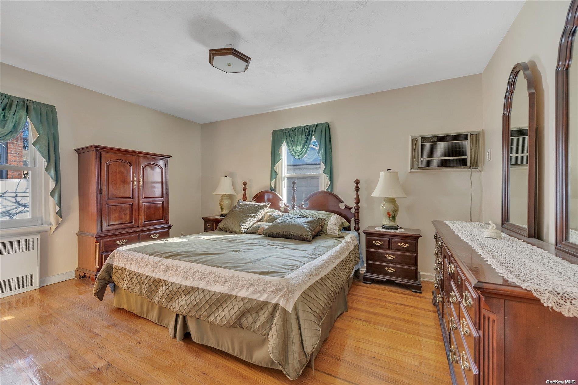 166-40 15th Drive Queens, NY 11357 - Photo 8 of 28 a bedroom with a bed and dresser with mirror