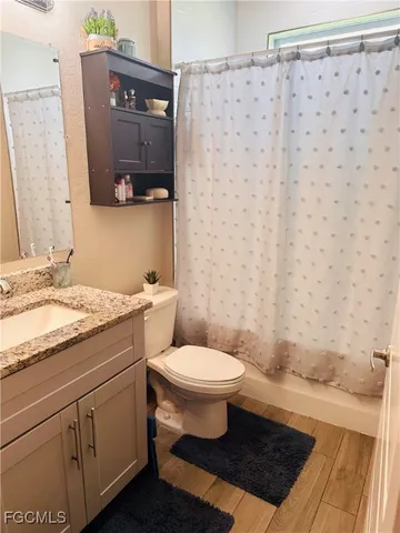 a bathroom with a granite countertop toilet sink and mirror