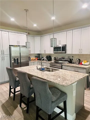 a kitchen with stainless steel appliances granite countertop a sink a stove a refrigerator a microwave oven with cabinets and wooden floor