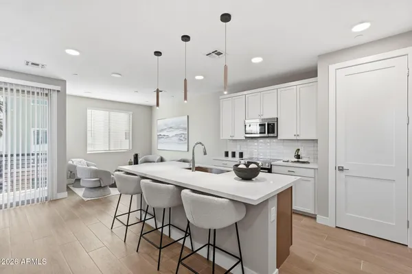 a kitchen with stainless steel appliances granite countertop a stove a sink a refrigerator and a dining table with wooden floor