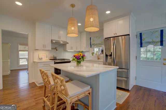 a kitchen with stainless steel appliances granite countertop a sink refrigerator and cabinets