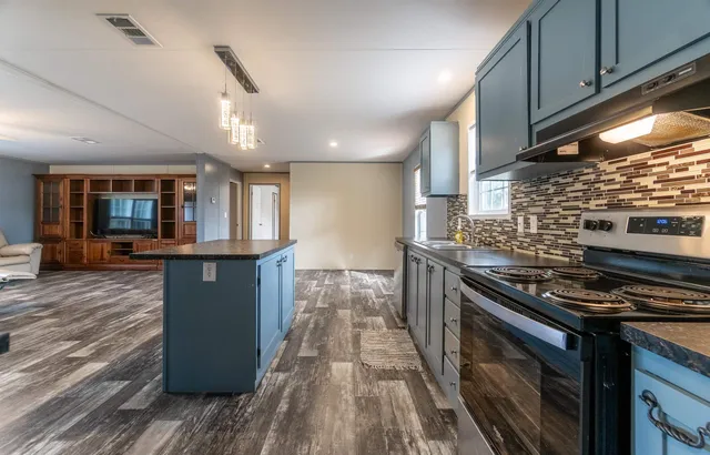 a kitchen with stainless steel appliances granite countertop a stove and a wooden floors