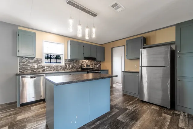 a kitchen with stainless steel appliances granite countertop a refrigerator a sink and a stove