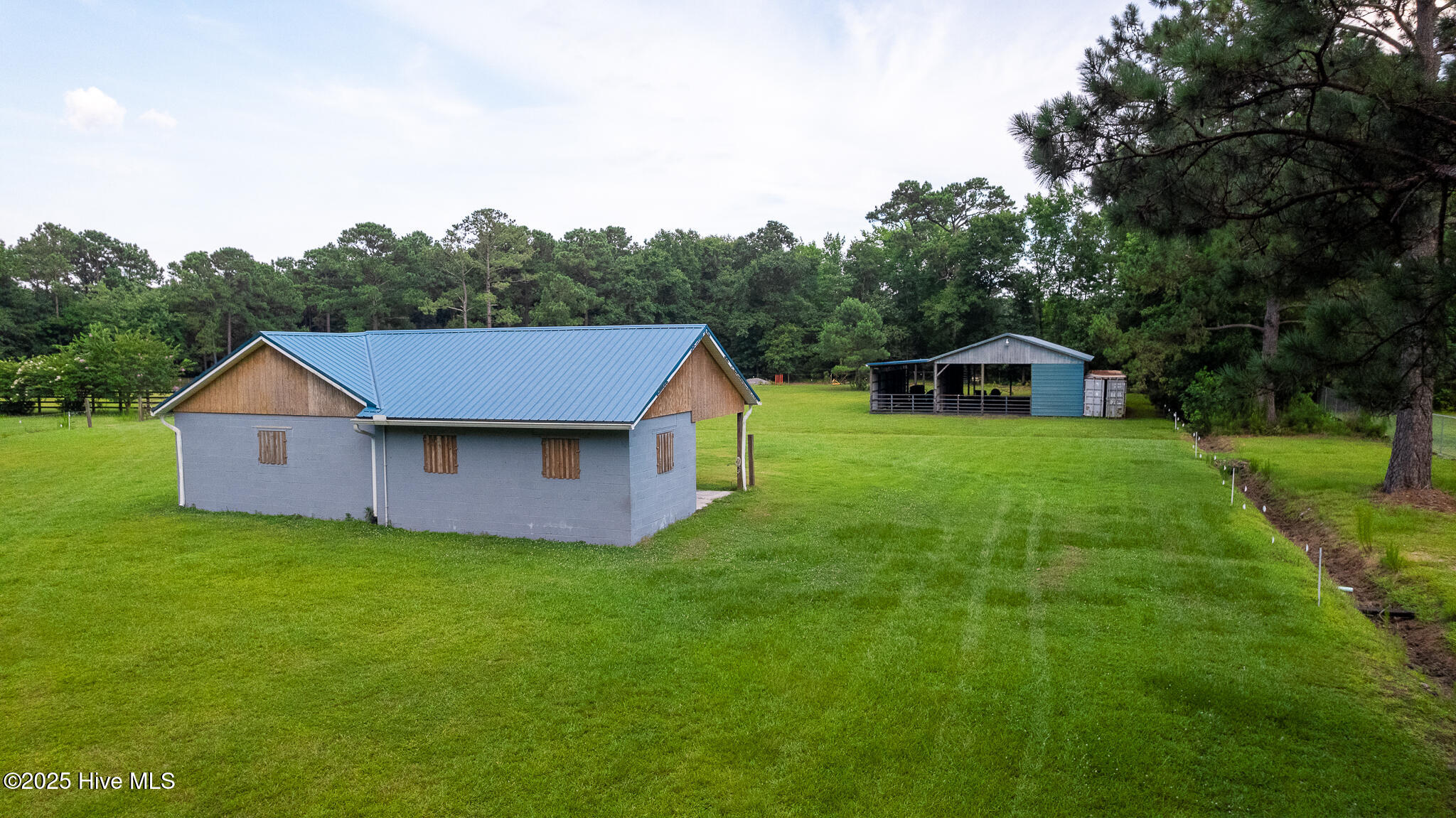 161 Howard Lane Swansboro, NC 28584 - Photo 30 of 56 Stable windows have functional shutters and night lighting for keeping check on the horses at night from the residence. Pole Barn #1 in background.