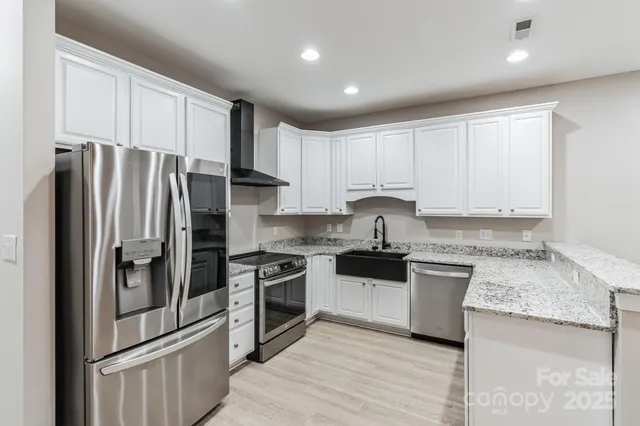 a kitchen with granite countertop a refrigerator stove and sink