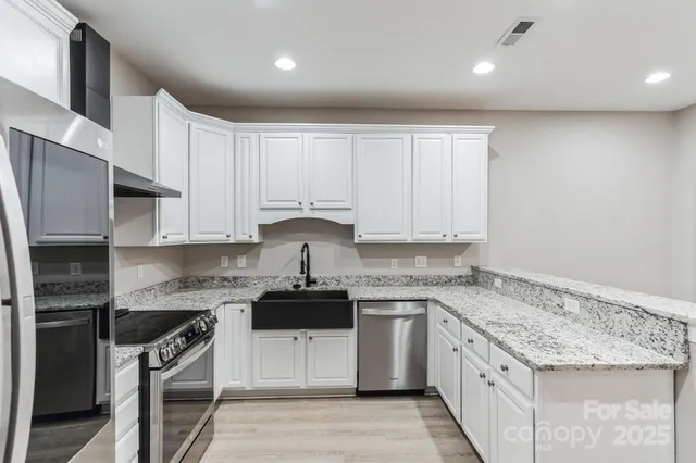 a kitchen with granite countertop white cabinets and stainless steel appliances