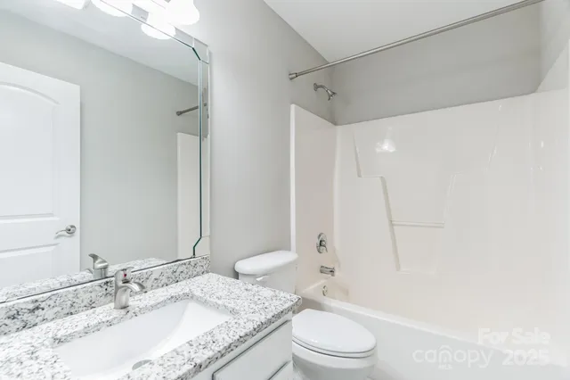 a bathroom with a granite countertop sink a toilet and shower