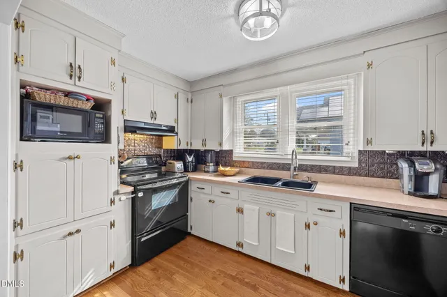 a kitchen with granite countertop a sink a stove a microwave and cabinets