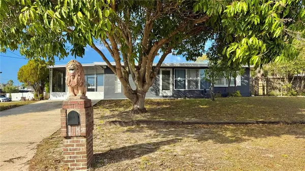 a front view of a house with a yard and large tree