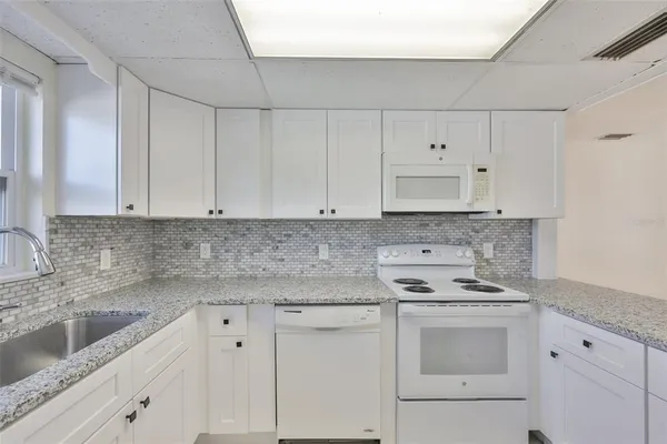 a kitchen with granite countertop white cabinets and white appliances