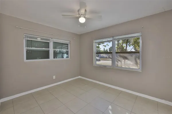 an empty room with windows and ceiling fan