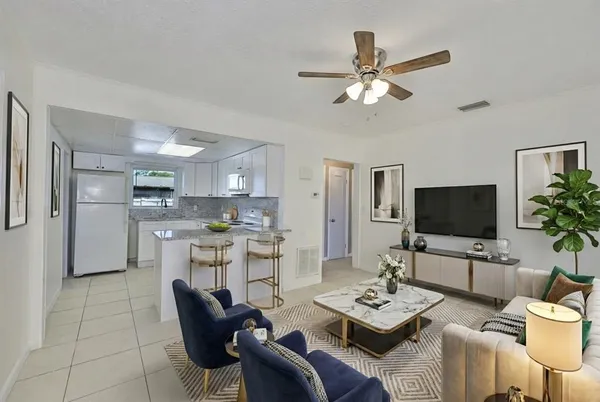 a living room with furniture kitchen view and a window