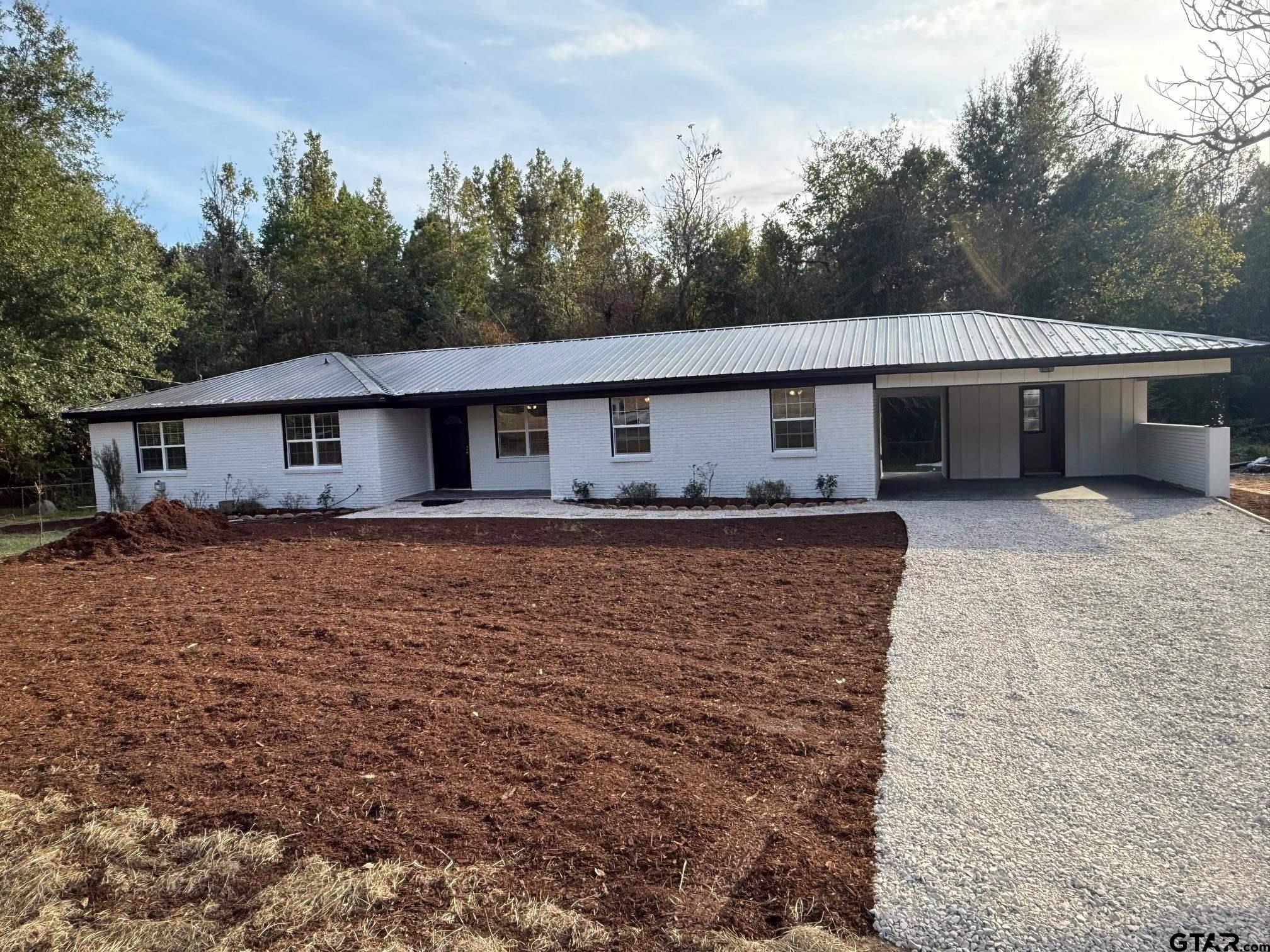 a front view of house with yard and trees in the background