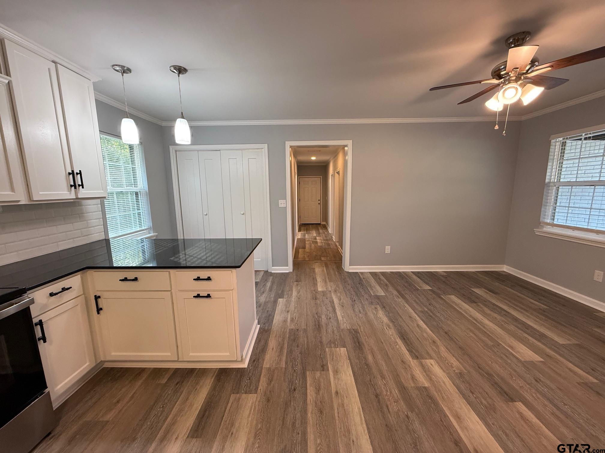 3248 Highway 79 Henderson, TX 75652 - Photo 13 of 44 a kitchen with granite countertop a stove a sink and white cabinets with wooden floor next to windows