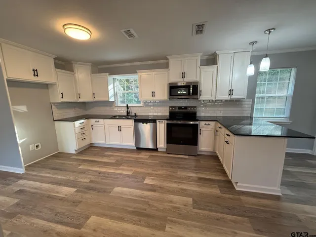 a large kitchen with stainless steel appliances granite countertop a stove a sink dishwasher and a refrigerator