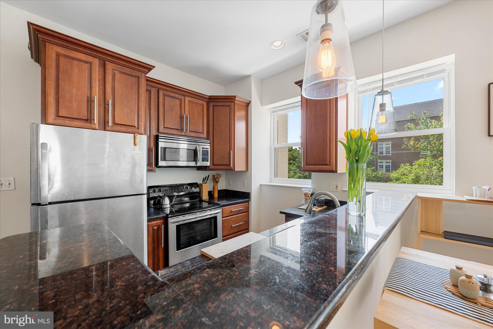 1124 E Street Northeast, Unit A Washington, DC 20002 - Photo 2 of 10 a kitchen with stainless steel appliances granite countertop a refrigerator a stove and a sink with wooden floor