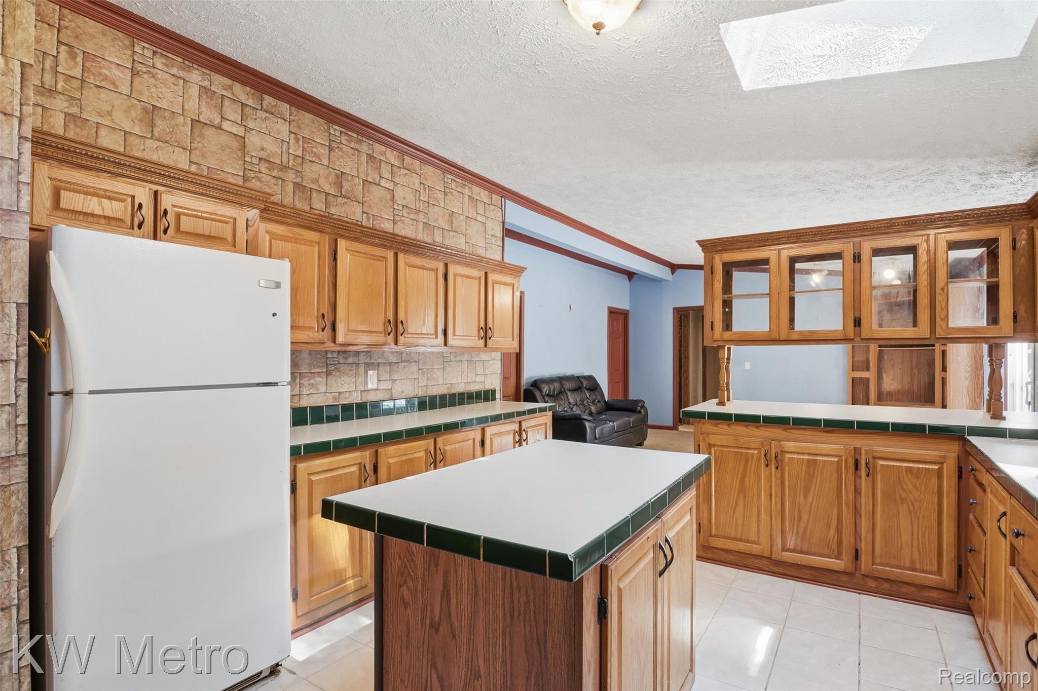 22733 Sumpter Road Belleville, MI 48111 - Photo 22 of 52 Kitchen featuring wood cabinetry, white tile flooring, a central island with a white countertop, and a skylight