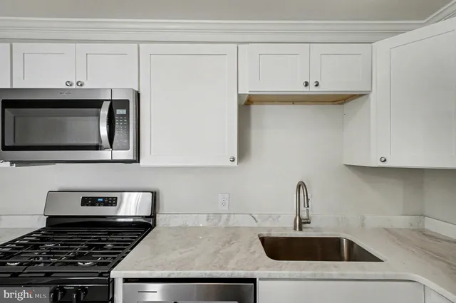 a kitchen with white cabinets and stainless steel appliances