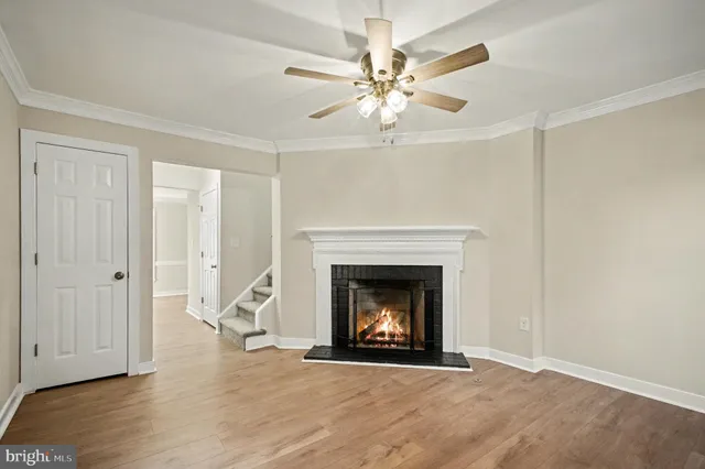 a view of an empty room with wooden floor and a fireplace