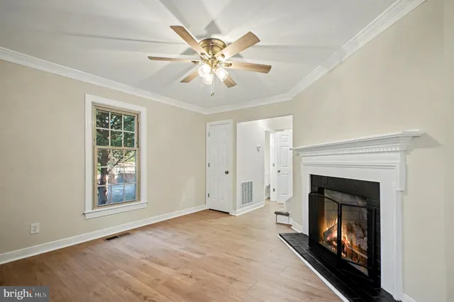 a view of an empty room with chandelier fan and fire place