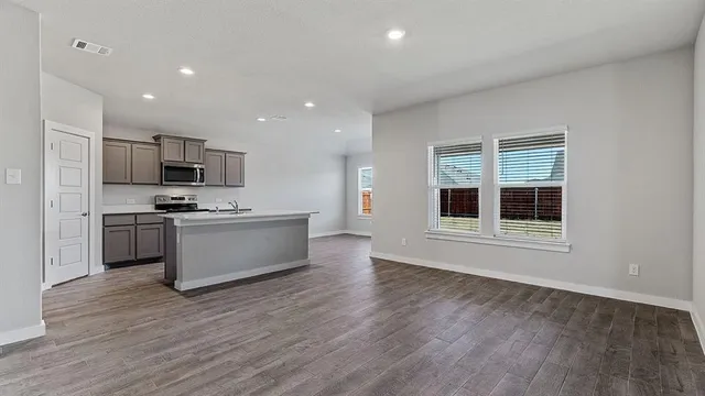 a large kitchen with a large counter top a sink stainless steel appliances and cabinets