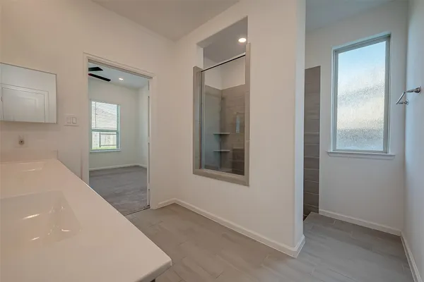 a spacious bathroom with a shower a sink and a mirror