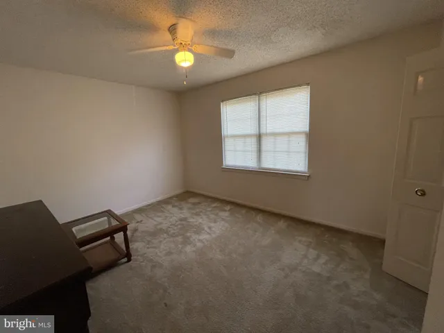 an empty room with windows and ceiling fan