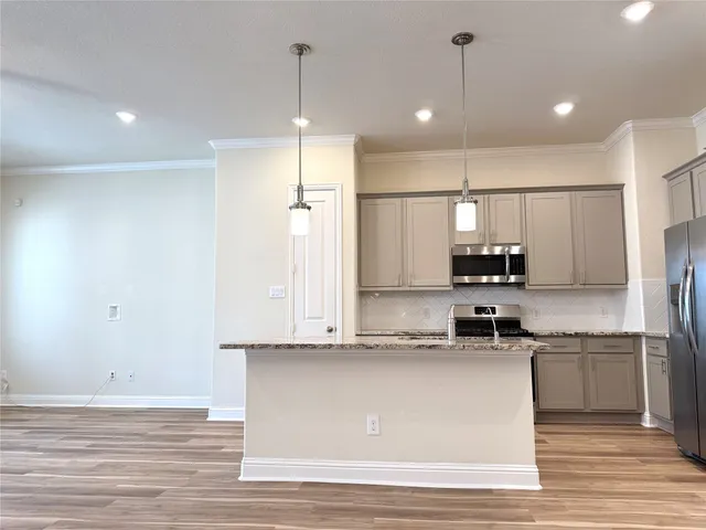 a kitchen with stainless steel appliances granite countertop a refrigerator a sink dishwasher a stove and white countertops with wooden floor