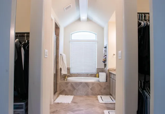 a view of a hallway with wooden floor and a bathroom