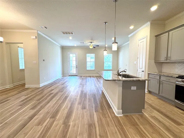 a kitchen with stainless steel appliances granite countertop a refrigerator a stove and a wooden floors