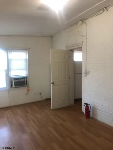 an empty room with wooden floor and window