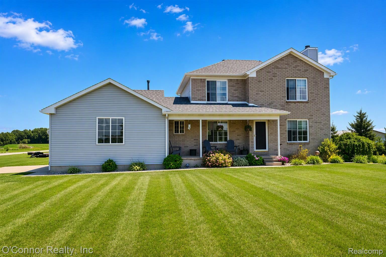 6870 Wildcat Road Jeddo, MI 48032 - Photo 2 of 5 Spacious residence featuring a covered front porch, a brick facade, and light gray siding